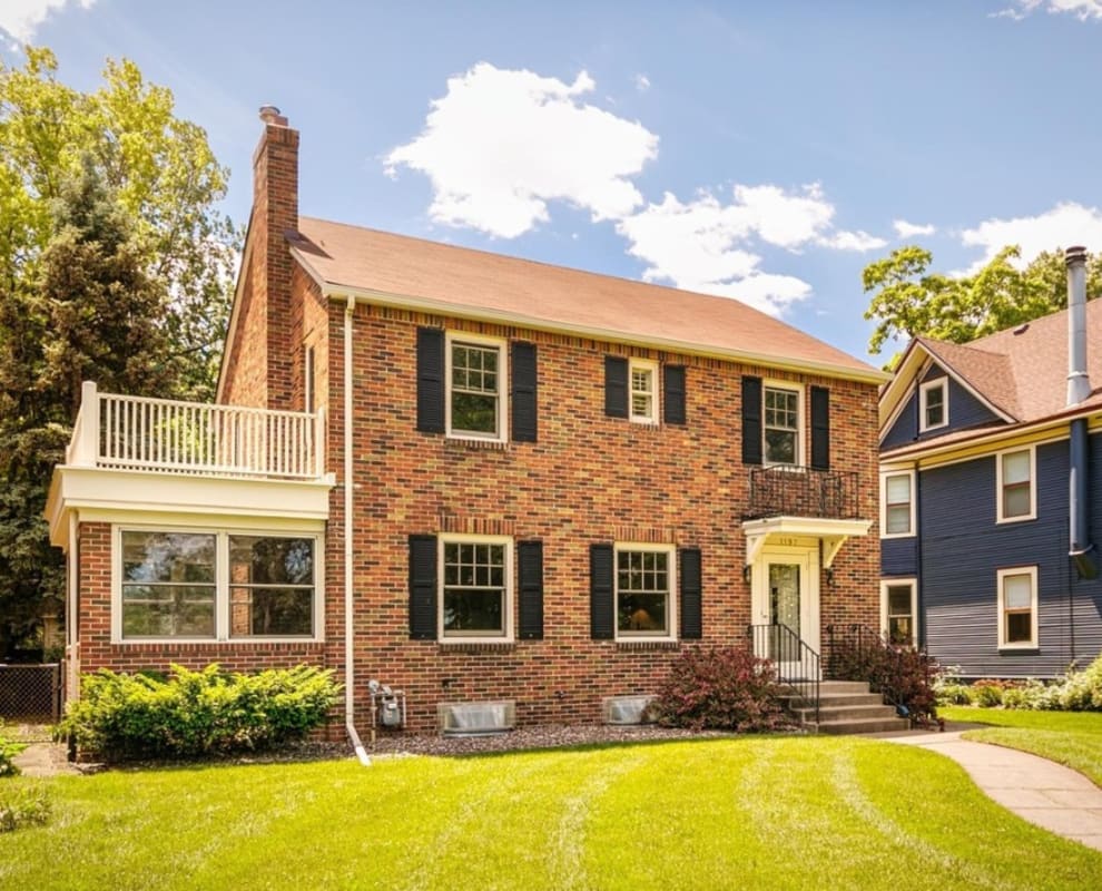 Charming brick colonial home featuring a welcoming balcony and well-maintained landscaping in a peaceful residential neighborhood.