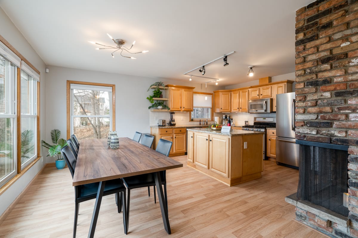 Your spacious open kitchen flows seamlessly into the dining area, where warm wood and exposed brick create the perfect gathering spot.
