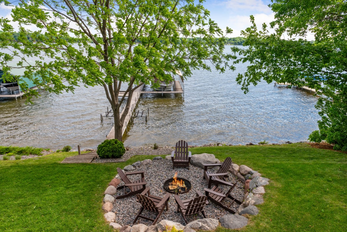 Gather around your private fire pit with lake views. Adirondack chairs circle the flames while your dock awaits peaceful evenings by the water.