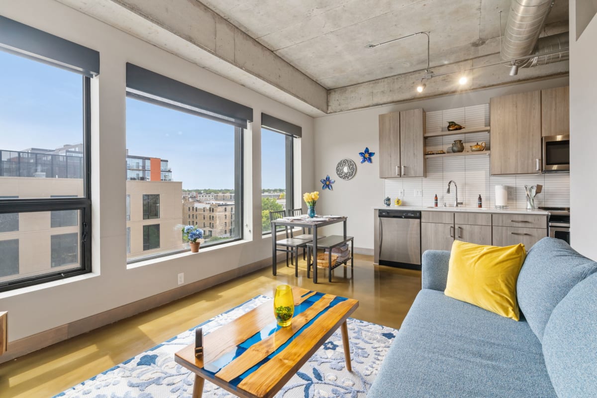 Relax in your bright, modern living space with floor-to-ceiling windows showcasing city views and a fully equipped kitchen for your stay.