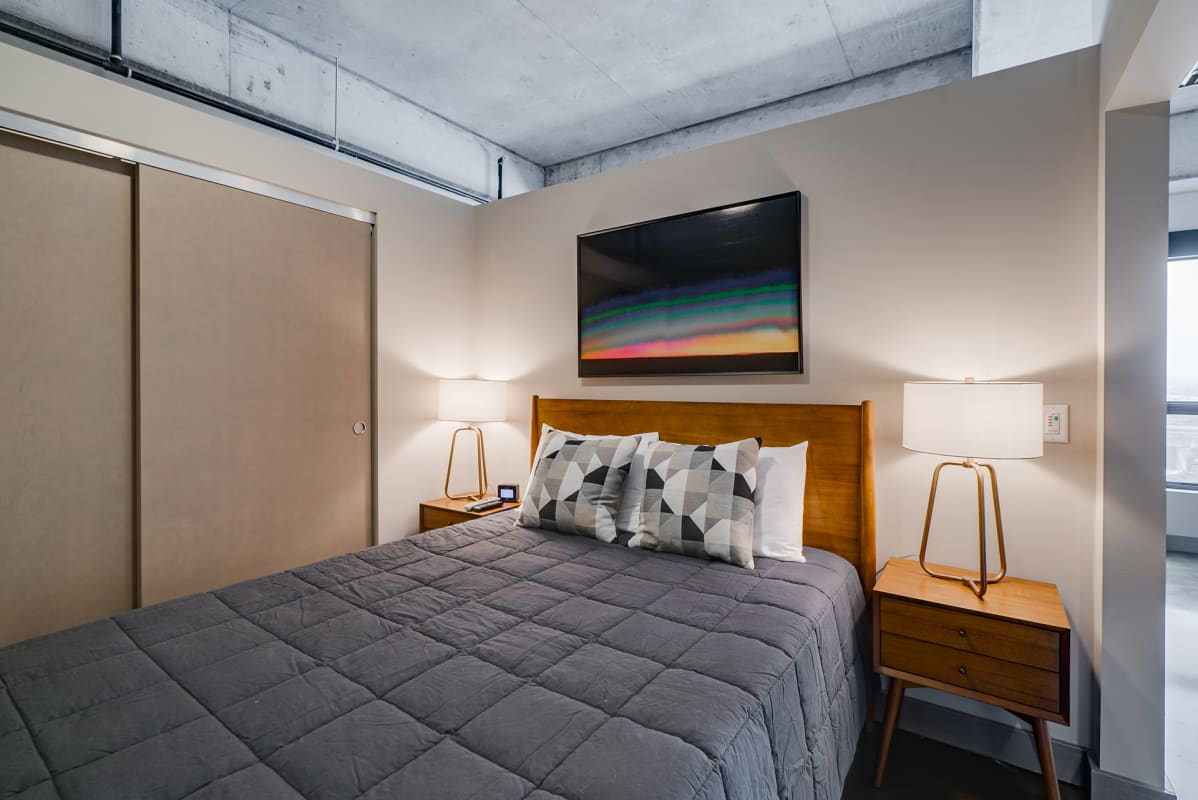 Your modern bedroom features warm wood furnishings and stylish geometric pillows, creating a cozy retreat with industrial charm.