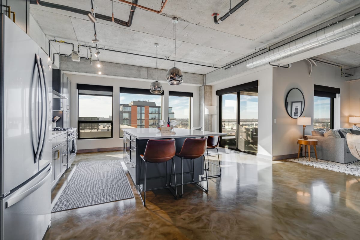 Step into your sleek urban loft with soaring ceilings, industrial charm, and a fully-equipped kitchen island perfect for morning coffee.