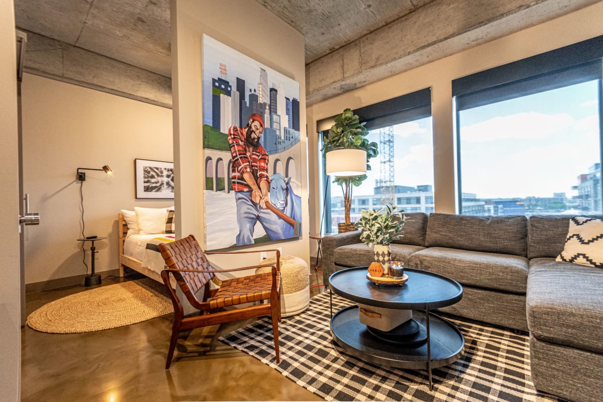 Unwind in your stylish living room with exposed concrete ceilings, vibrant artwork, and city views through floor-to-ceiling windows.