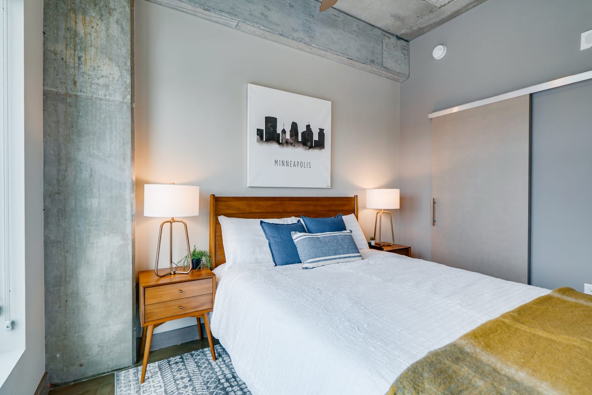 Relax in your stylish bedroom with exposed concrete details, soft lighting, and crisp white bedding that promises restful nights.