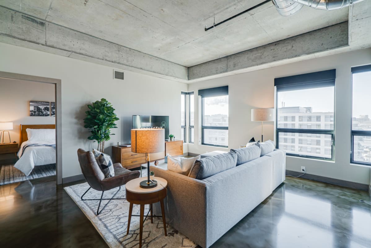 Relax in your stylish industrial loft with exposed concrete ceilings, modern furnishings, and bright city views flooding through oversized windows.