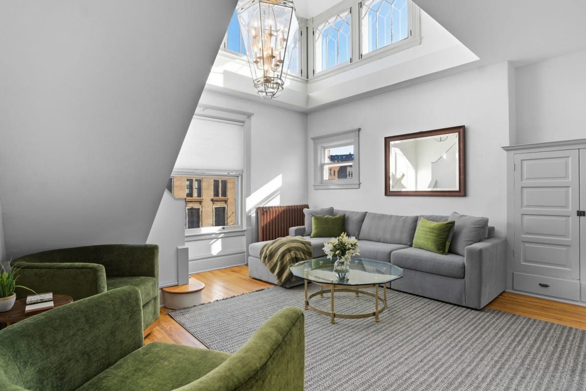 Unwind in your light-filled living room, where soaring skylights and emerald velvet seating create a luxurious retreat beneath the clouds.