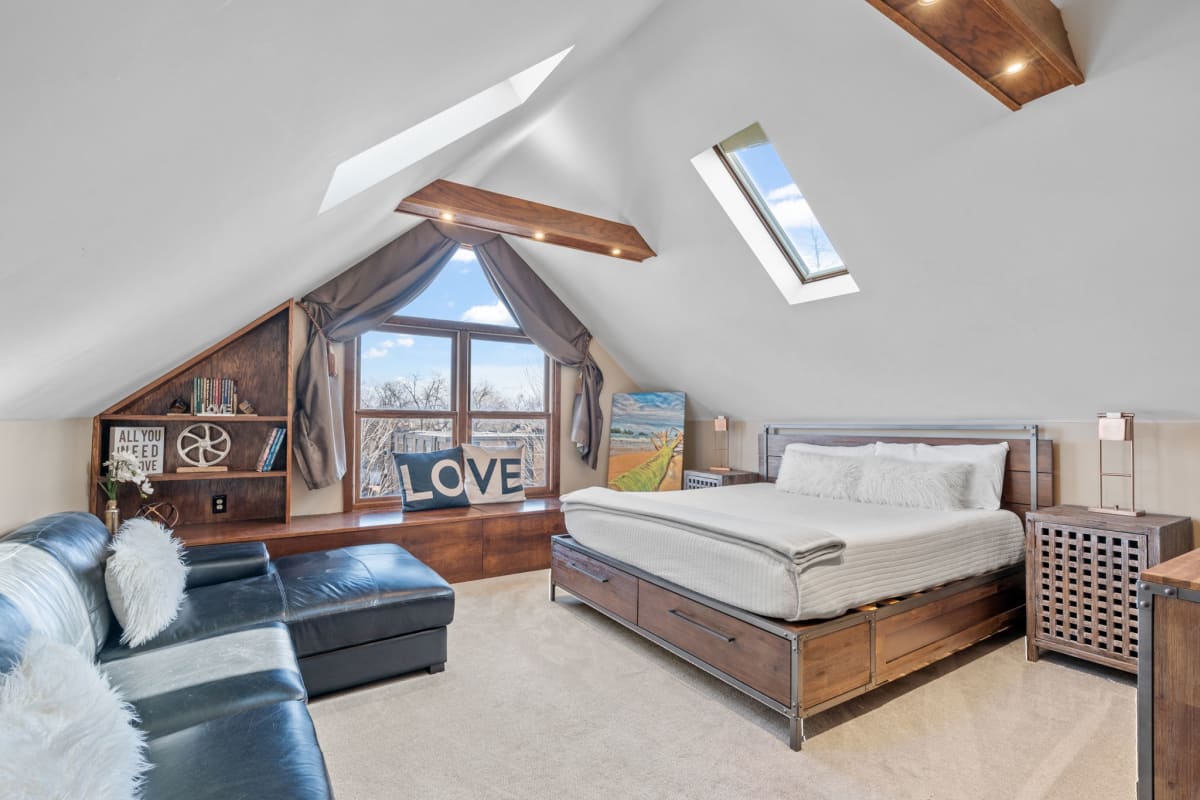 Unwind in your charming loft bedroom where exposed wooden beams frame skylights that flood the space with natural light.
