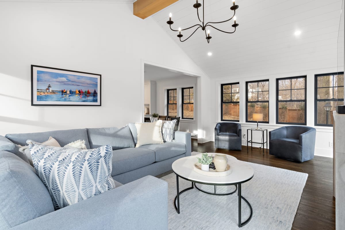 Relax in your bright living space with plush sectional seating, exposed beams, and elegant chandelier creating the perfect gathering spot.