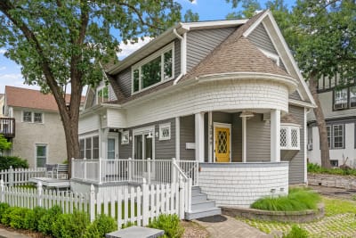 Victorian-style house featuring a turret, gray exterior, and a bright yellow door.