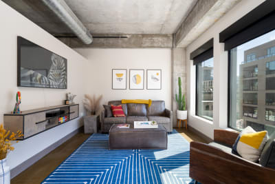 Contemporary living room with a leather sofa, artistic prints, and large windows.
