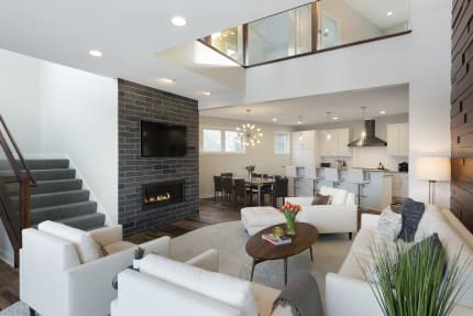 Modern living room with white sofas, a dark stone fireplace, and a dining area in the background.