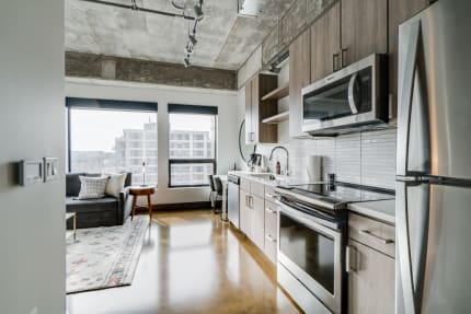 A stylish kitchen and living area featuring stainless steel appliances and large windows.
