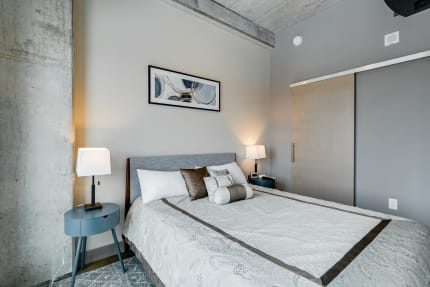 A contemporary bedroom featuring a neatly made bed, beside lamps, and modern artwork.