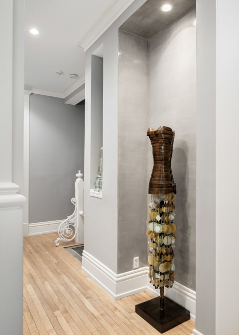 Sculptural dress form with metallic bodice and pastel circular decorations in a modern entryway.