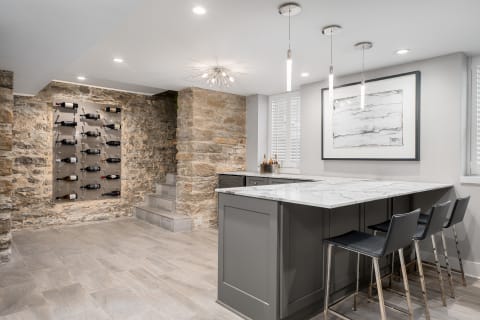 Modern basement bar featuring stone walls, marble countertops, and stylish wine storage.