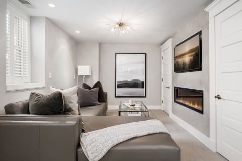 A modern living room featuring a dark leather couch, a glass coffee table, and a stylish fireplace, creating a warm and inviting atmosphere.