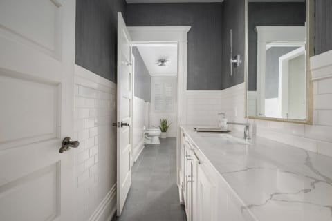 A modern bathroom with marble countertops, white subway tiles, and gray accent walls, showcasing a serene ambiance.