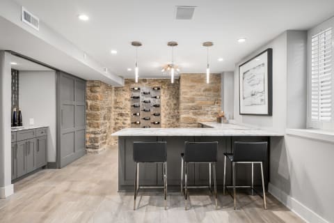 Modern kitchen with marble countertop, stone accent wall, and wine storage.