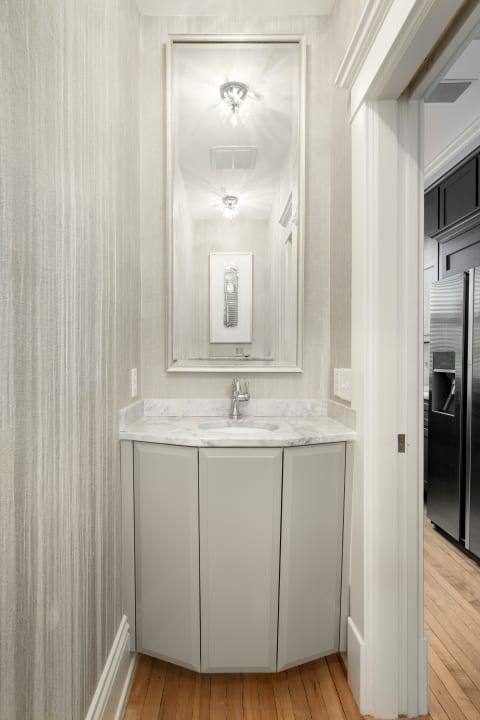 Elegant powder room with a marble countertop, sophisticated lighting, and textured wallpaper.