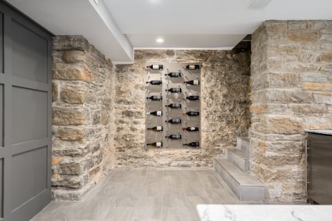 A modern wine storage area with stone walls and a sleek wine rack.