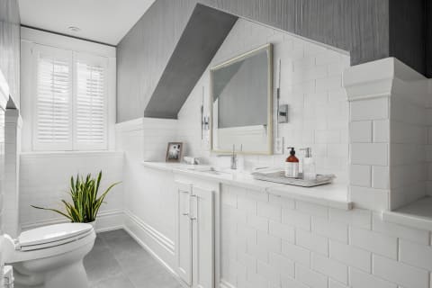 Stylish bathroom with white subway tiles, marble vanity, and plant decor.