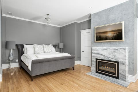 Elegant bedroom with a plush bed, cozy fireplace, and serene decor elements.