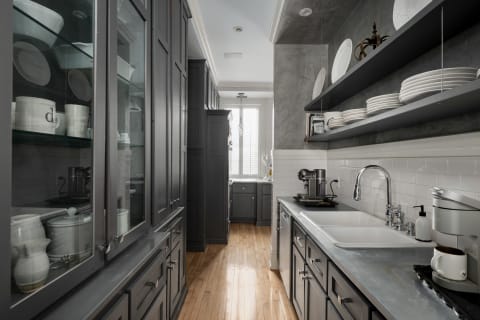 A gourmet galley kitchen featuring gray cabinetry, marble countertops, and modern appliances.