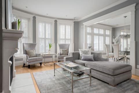 Cozy gray living room with elegant furniture and natural light from large windows.