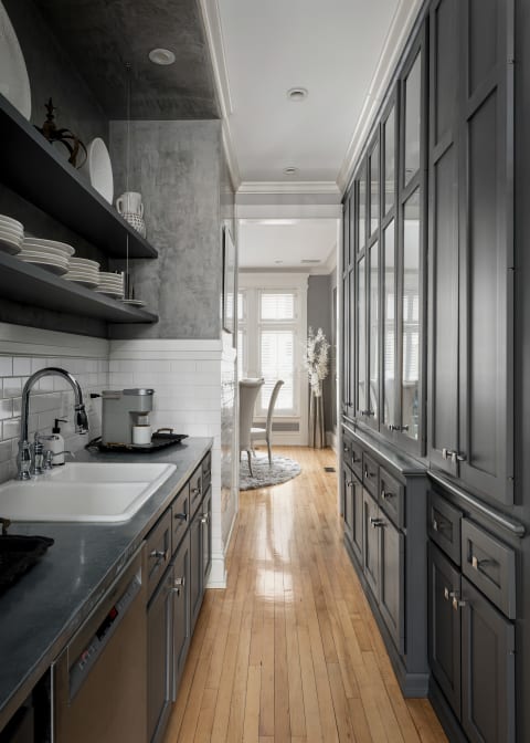 Galley kitchen with gray cabinets, stainless steel appliances, and a view of a dining area.