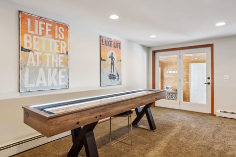 Interior view of a game room with shuffleboard table and inspirational lake-themed artwork.