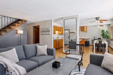 An inviting living room with a gray sofa, black chairs, and an adjoining kitchen area.