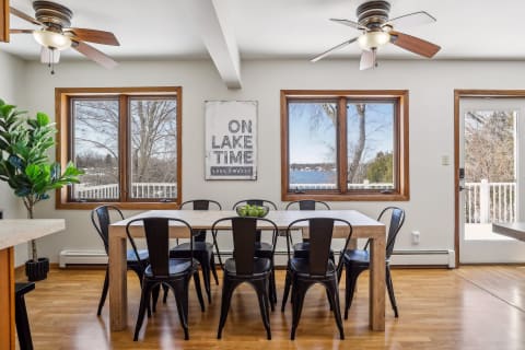 Dining area featuring a wooden table with black chairs and large windows showcasing lake views.
