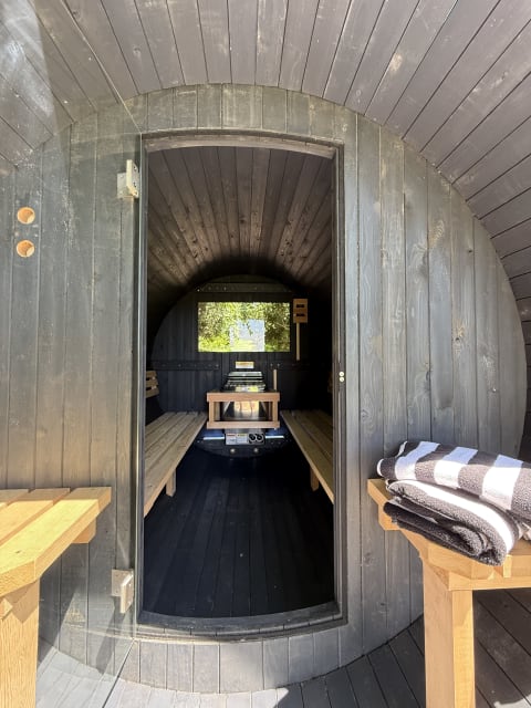 Interior of a barrel sauna with wooden benches and a view outside.