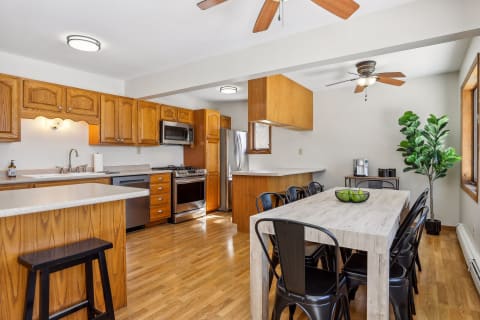 Spacious kitchen featuring wooden cabinetry, modern appliances, and a dining area with a rustic table and chairs.