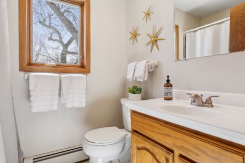 A bright bathroom featuring warm wood accents, white towels, and modern starburst decor.