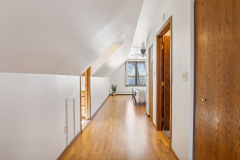 A serene hallway with a sloped ceiling, hardwood floor, and a view of a nearby lake through a window.