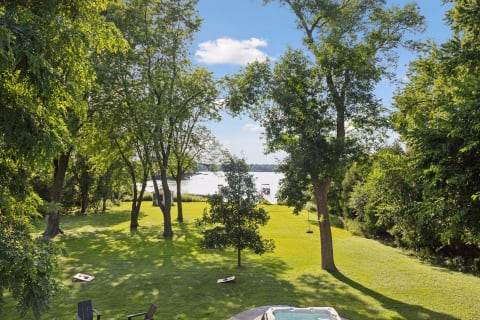 Lush waterfront grounds with trees, a lawn, and a view of a peaceful lake.