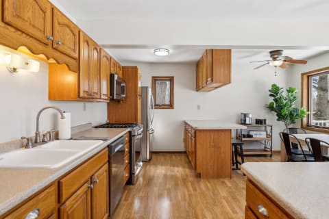 Bright kitchen with wood cabinets, stainless steel appliances, and a dining area with metal chairs.