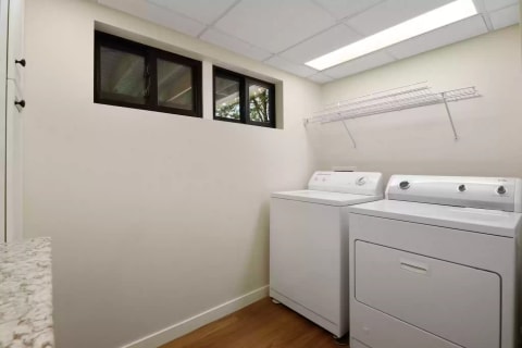 Bright laundry room featuring a washing machine, dryer, and natural light from windows.
