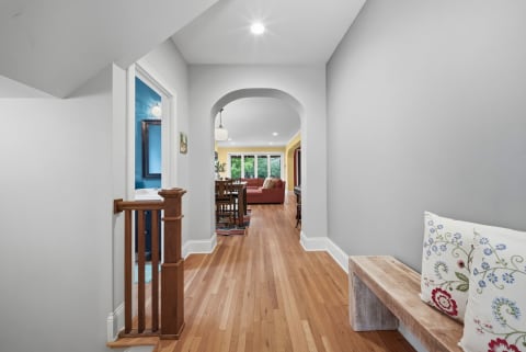 Bright hallway leading to archway and living spaces with warm hardwood floors.
