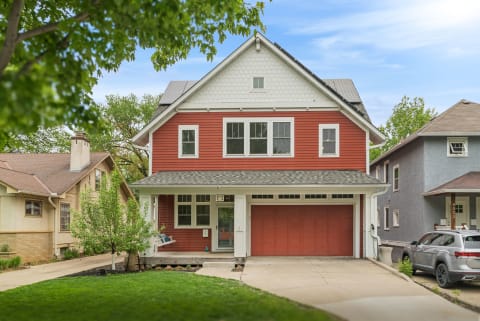 A modern red home with a spacious driveway and garage set in a quiet residential area.