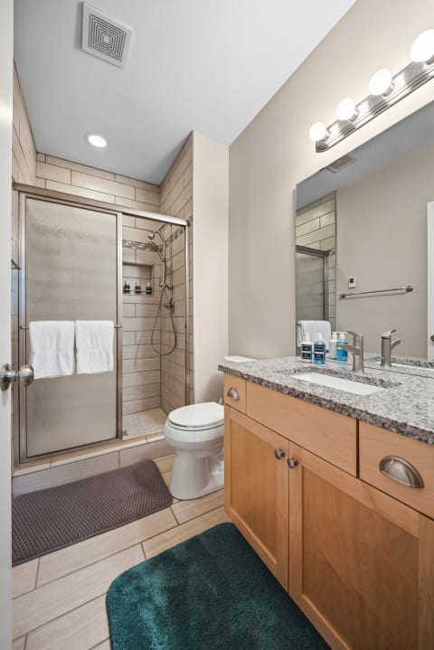 Modern bathroom featuring a walk-in shower with a granite vanity and fresh towels.