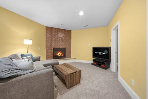 Cozy living room featuring a plush sofa, a fireplace, and a television.