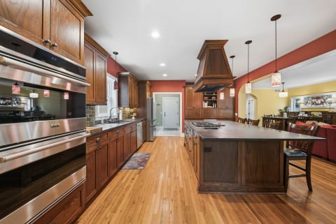 A gourmet kitchen with dark wood cabinets, stainless steel appliances, and a large central island with bar stools.
