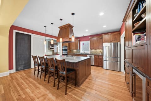 Spacious kitchen featuring a large wooden island with seating, modern stainless steel appliances, and rich cabinetry.
