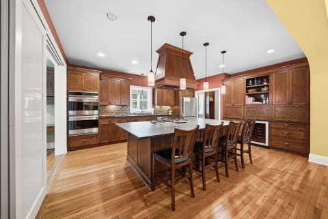 A spacious kitchen featuring dark wood cabinetry, modern stainless appliances, and a central island with seating.