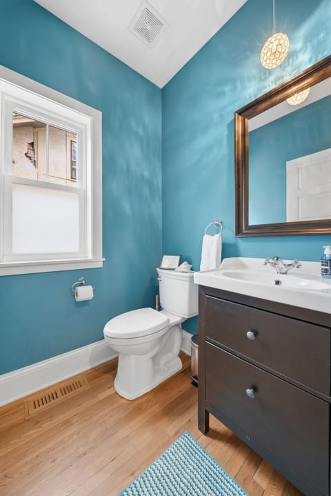 A half bathroom with turquoise walls, a white toilet, and a dark wooden vanity.
