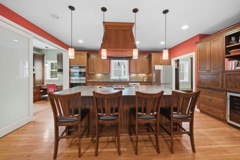A spacious kitchen with a large wooden island, pendant lighting, and modern appliances.