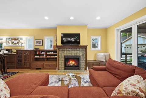 Cozy living room with yellow walls, fireplace, and orange sofas.