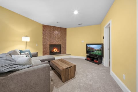 A warm living room with a yellow wall, a sectional sofa, and a fireplace.
